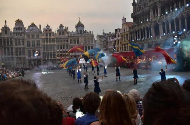 Performers toss flags in the air during a performance in a city's courtyard.