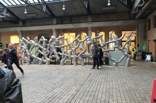 People gather around a metal sculpture outside.