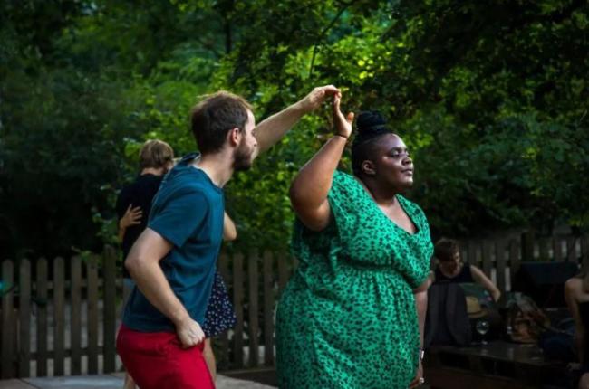 Two students dance together in on a garden patio.