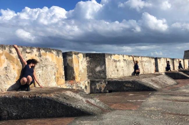 Dancers perform outside against an ancient wall.